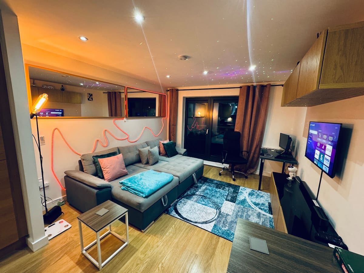 Living room with corner sofa, TV and colourful smart lighting